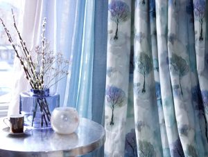Curtains with delicate tree designs in hues of blue on cream background - Blinds Norfolk - Norwich Sunblinds